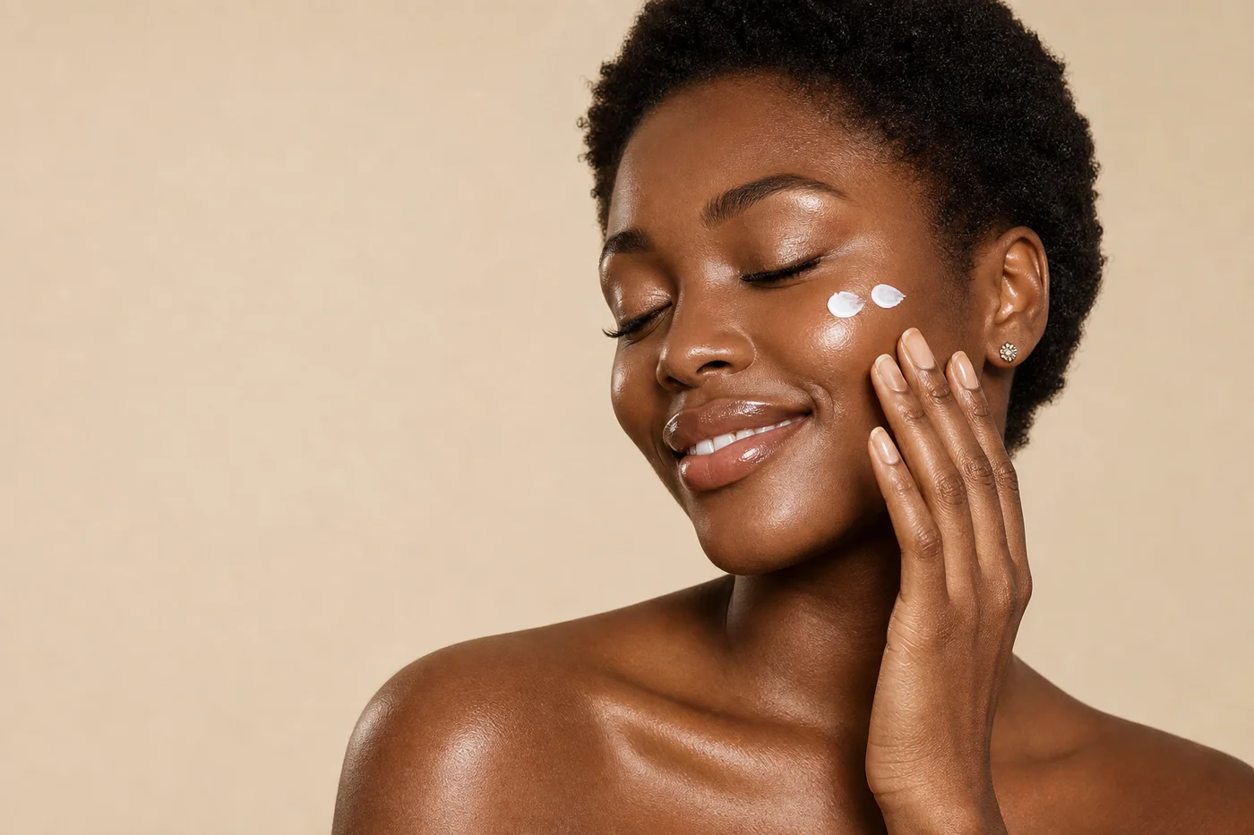 Nigerian woman with glowing skin applying sunscreen to her cheek